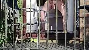naughty girl enjoys wanking in full view on the balcony