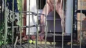 naughty girl enjoys wanking in full view on the balcony