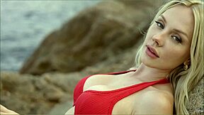 Blonde woman has sex with lifeguard on the beach behind rocks