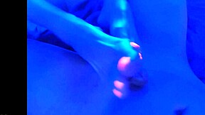 suggestive blacklight fetish with feet, toes, and footjob in dark setting.