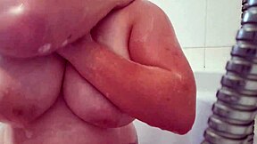 Busty teen washes and massages soapy breasts.