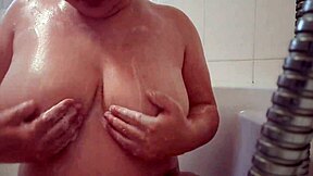 Busty teen washes and massages soapy breasts.