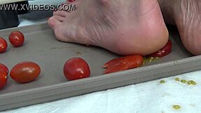This mature housewife enjoys trampling tomatoes with her bare feet in a fun kitchen activity
