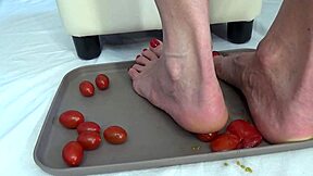 This mature housewife enjoys trampling tomatoes with her bare feet in a fun kitchen activity
