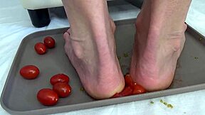 This mature housewife enjoys trampling tomatoes with her bare feet in a fun kitchen activity