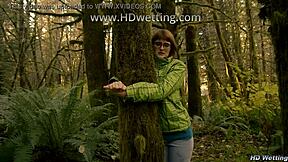 bound and handcuffed to forest tree she squirms desperate for pee release in nature accident