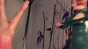 Redhead mistress in latex dominates flogging bound sub hard