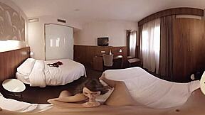 VR porno představuje brunetku v hotelovém pokoji.